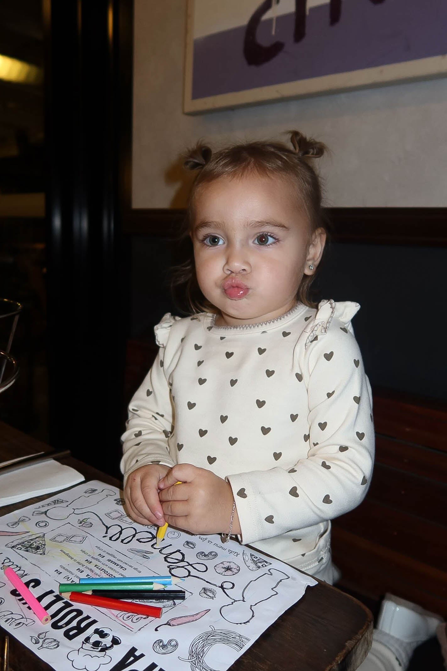 Child sitting at a table with coloring books and crayons, indoors.