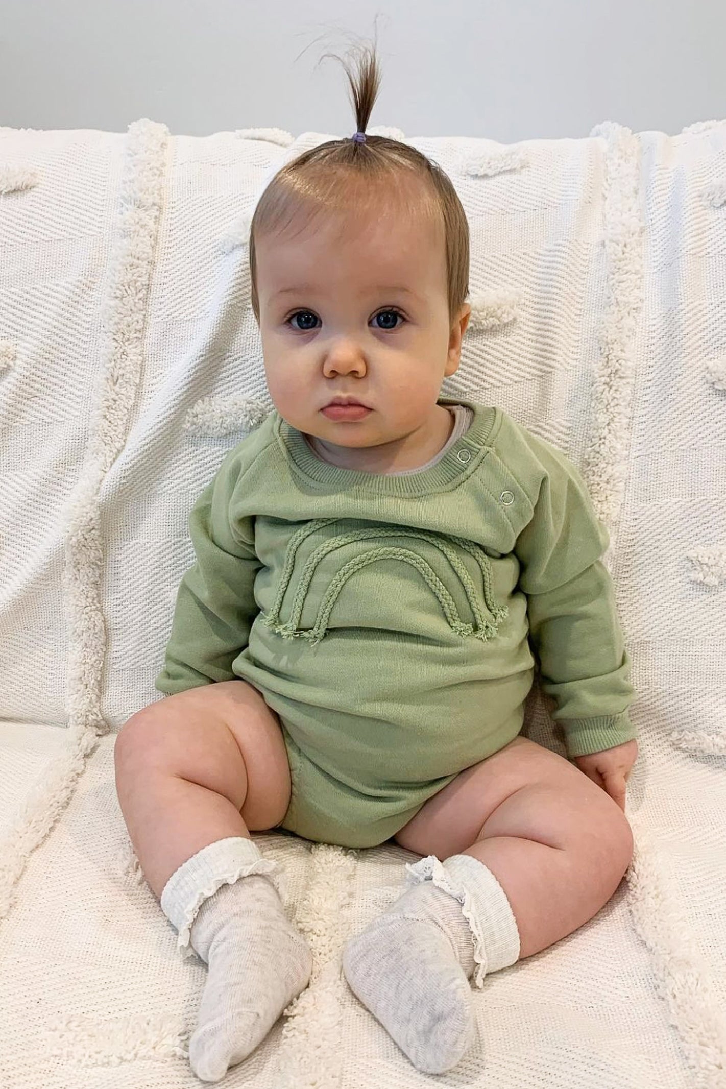baby wearing green bodysuit